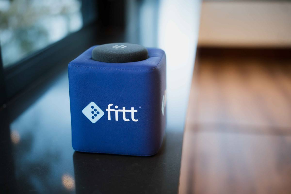 A blue Fitt-branded cushion cube resting on a polished table by the window.