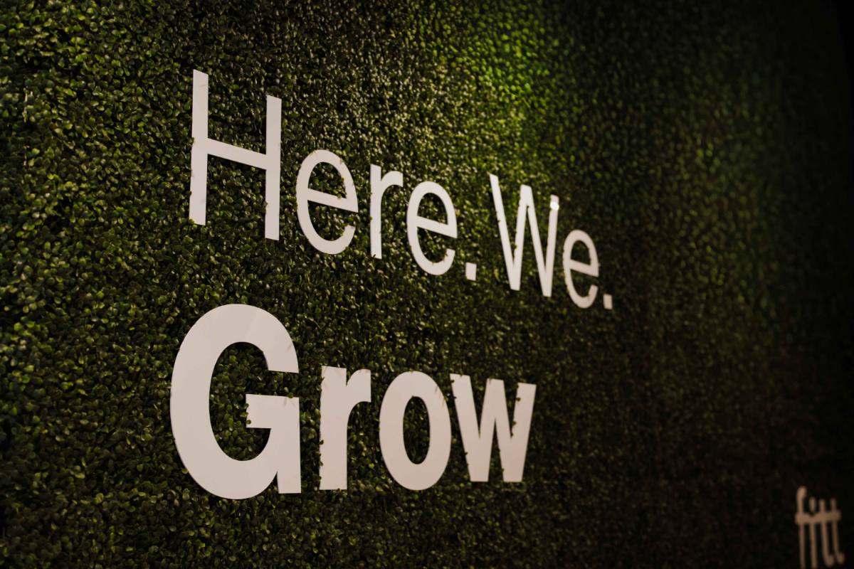 Close-up of the &lsquo;Here. We. Grow.&rsquo; lettering on the green living wall.