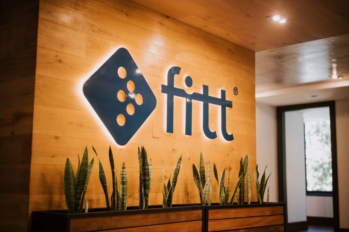 Fitt reception with the illuminated Fitt logo on a timber wall.